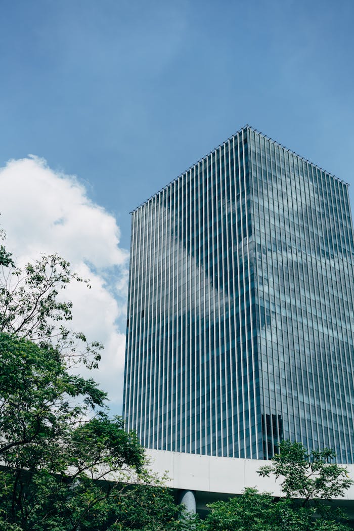 The Art of Drawing Readers In: Your attractive post title goes here A modern glass skyscraper reflects a blue sky, surrounded by greenery.